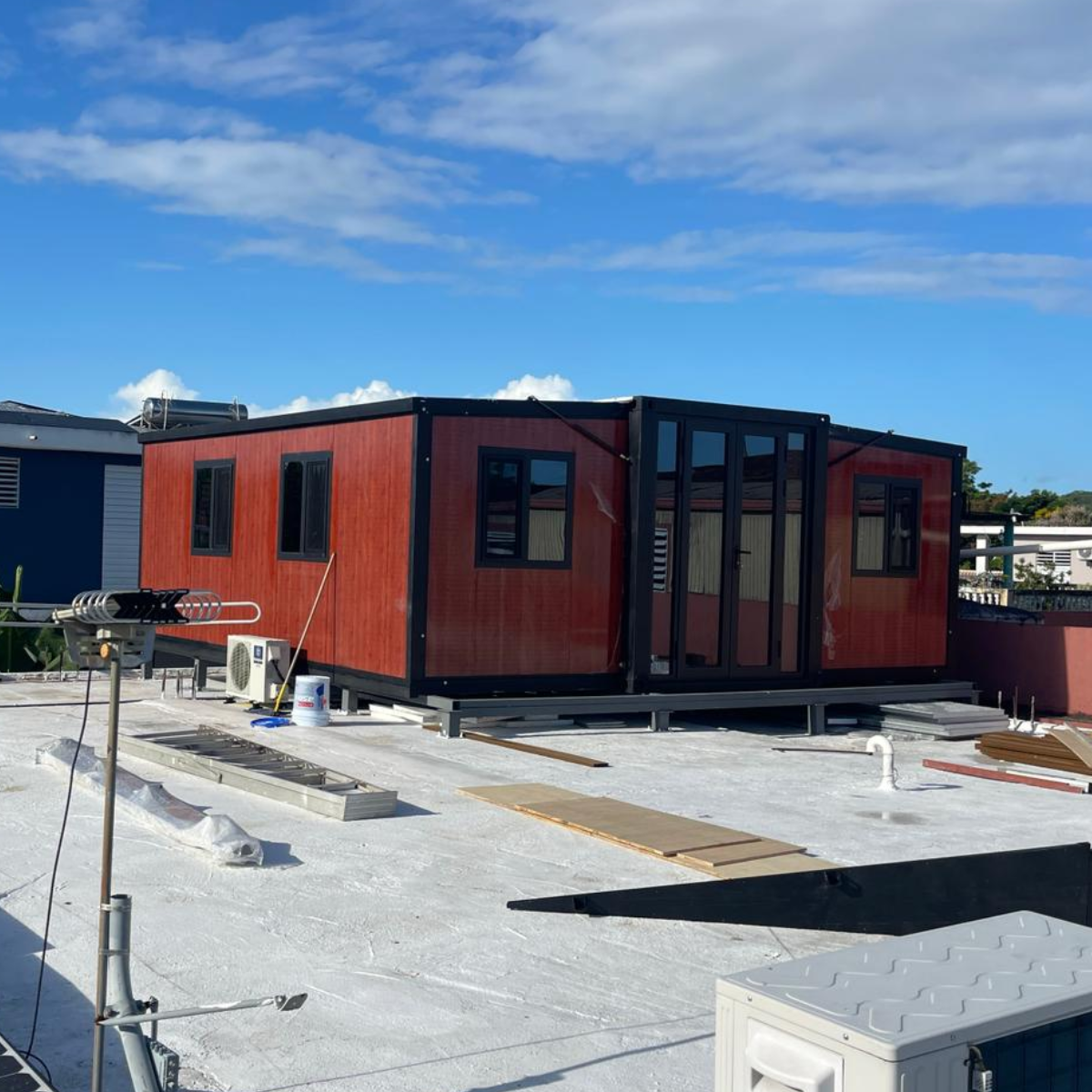 Container-style buildings on a rooftop with solar panels and clear sky.